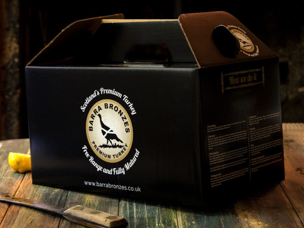 A black turkey packaging box with text and logo, on a rustic wooden surface with a lemon slice