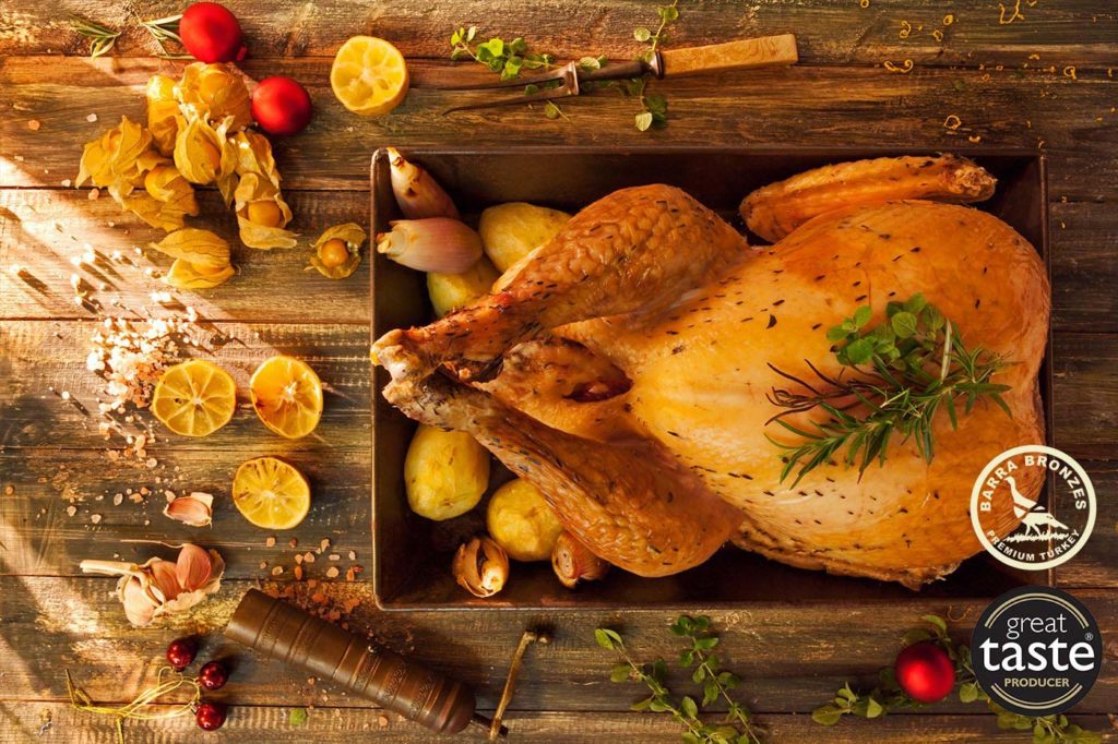 barra bronzes christmas turkey Roasted turkey with herbs, lemons, and spices on a rustic wooden table.