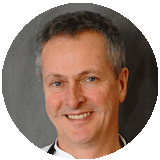 A man with short grey hair wearing a black and white shirt.